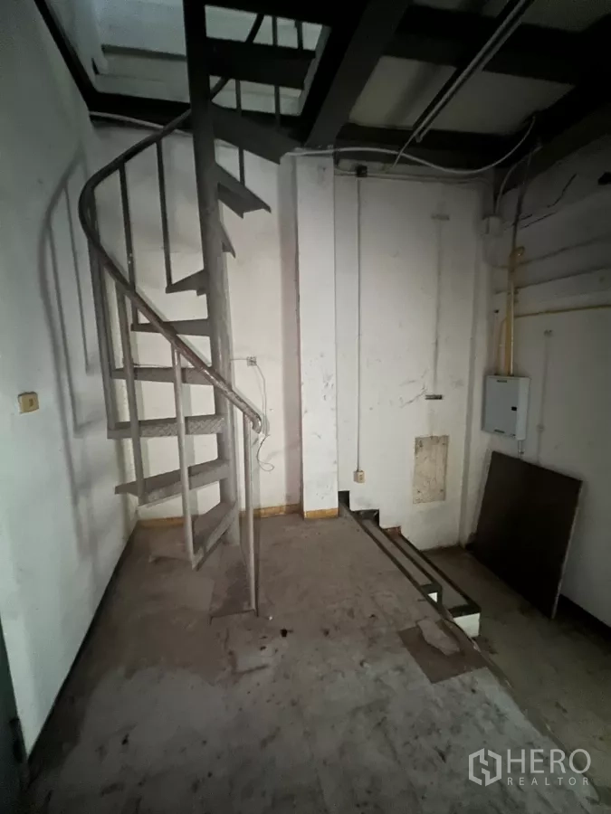 零售空间 出租在Watthana, Bangkok - 旋转楼梯通向夹层储物区，墙面可见管线。