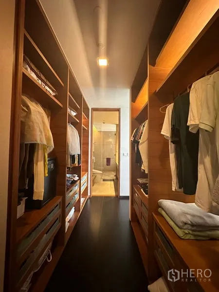 Condominium for rent or sale in Sathon, Bangkok - Walk-in closet corridor with custom wooden shelving leading to an ensuite bathroom.