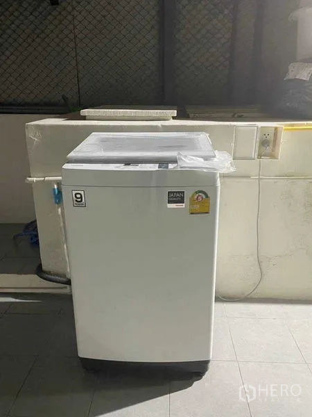 Home Office for rent or sale in Watthana, Bangkok - Top-load washing machine on a tiled utility balcony with power outlet and sink.