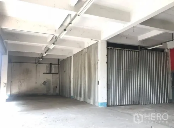 货栈 出租在Bueng Kum, Bangkok - 带金属推拉门的储物区，混凝土梁顶与连续日光灯。