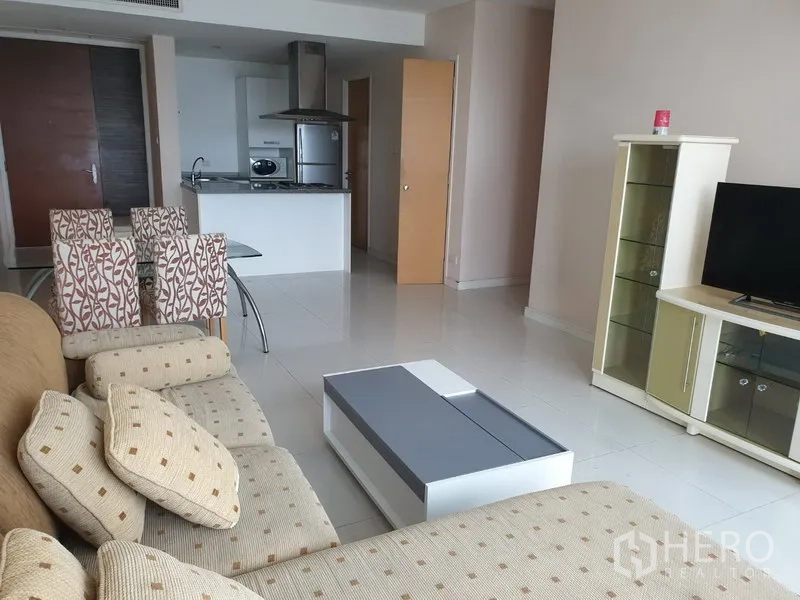 คอนโด ให้เช่าในWatthana, Bangkok - ห้องนั่งเล่นแบบเปิดโล่ง โซฟาสีเบจ ตู้ทีวี โต๊ะกลาง และเคาน์เตอร์ครัวพร้อมตู้เย็นสแตนเลส