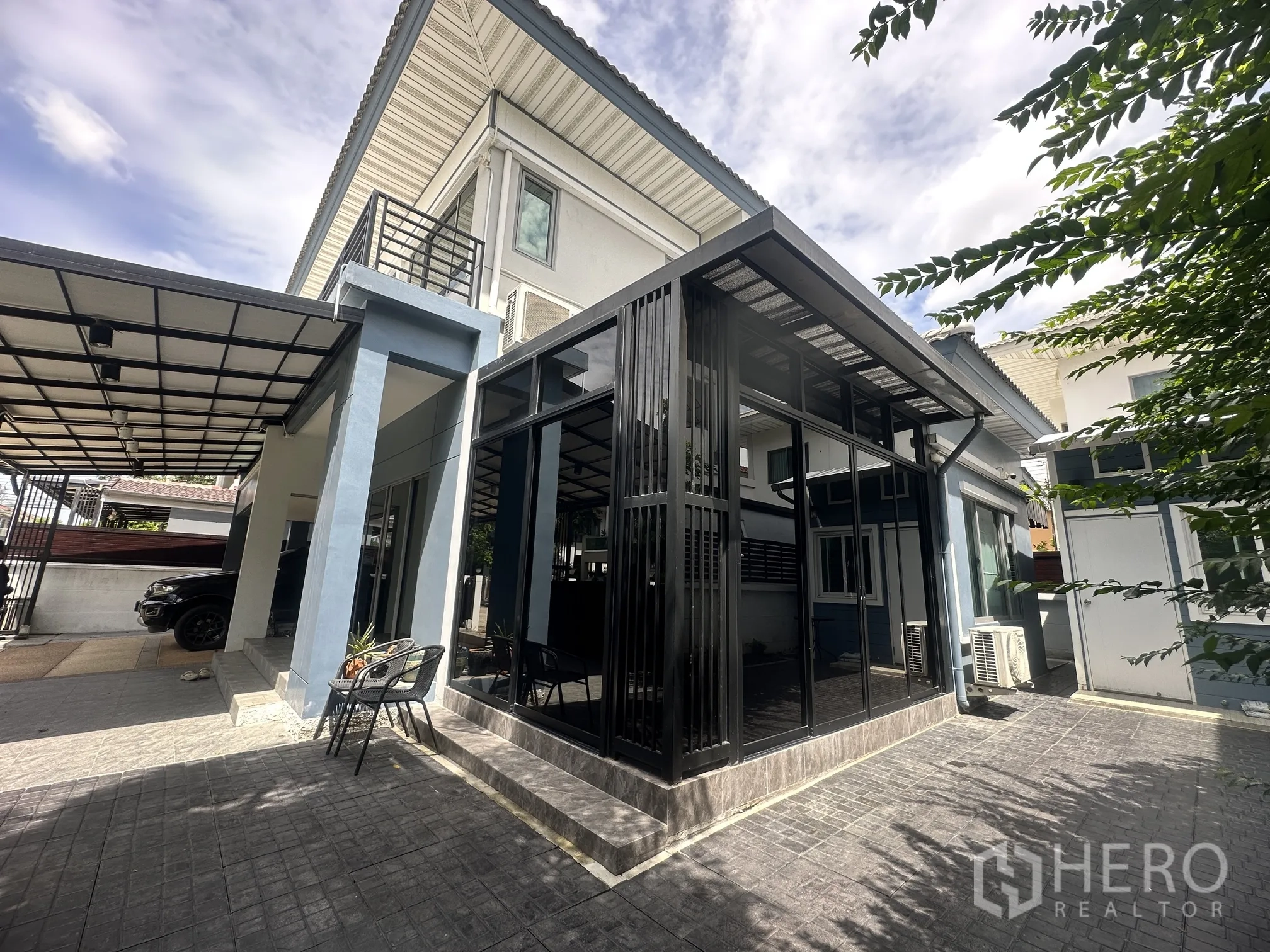 Detached House for sale in Pak Kret, Nonthaburi - Side patio with glass-enclosed room, carport canopy, and paved yard.