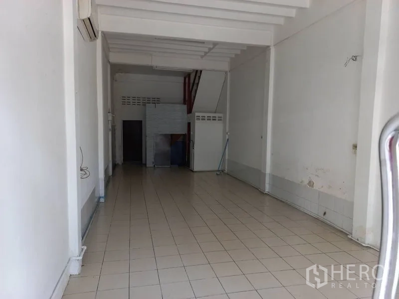 อาคารพาณิชย์ ให้เช่าในKhlong Toei, Bangkok - ชั้นล่างพื้นที่เปิดโล่งของอาคารพาณิชย์ ผนังสีขาว พื้นกระเบื้อง คานเพดานสูง และโซนบริการด้านหลังพร้อมประตูห้องน้ำ