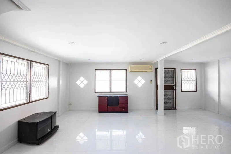 Home Office for rent in Watthana, Bangkok - Spacious white-tiled room with window grilles, air-conditioner, and cabinetry for office setup.