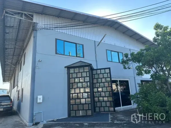 คลังสินค้า ให้เช่าในSaphan Sung, Bangkok - อาคารโกดังสองชั้น ด้านหน้าเป็นประตูเหล็กบานพับ หน้าต่าง และหลังคาทรงจั่ว