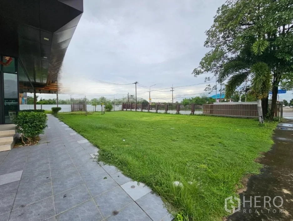 คลังสินค้า ให้เช่าในLam Luk Ka, Pathum Thani - ทางเดินและสนามหญ้าริมอาคารสำนักงานกระจกใกล้ถนนใหญ่