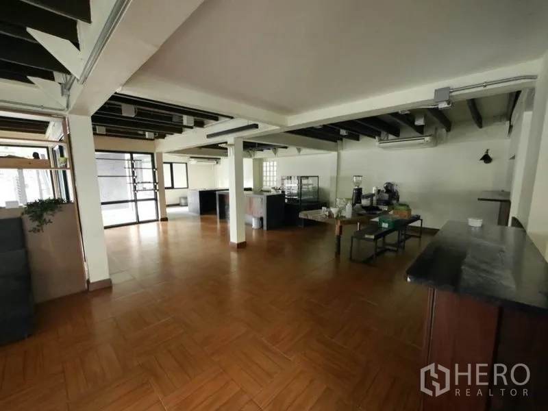 พื้นที่ขายปลีก ให้เช่าในKhlong Toei, Bangkok - พื้นที่ค้าปลีกแบบเปิด พื้นลายไม้ คานเปลือย พร้อมประตูกระจกและเคาน์เตอร์บริการ.