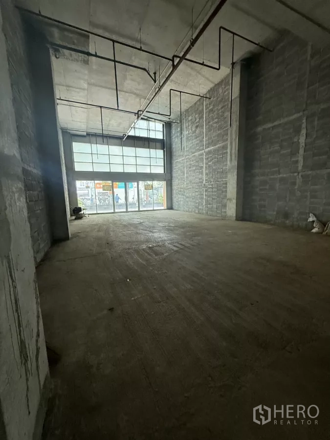Retail Space for rent in Bang Rak, Bangkok - Spacious raw concrete shop space with high ceiling, block walls, and a full-height glazed entrance ready for custom fit‑out.