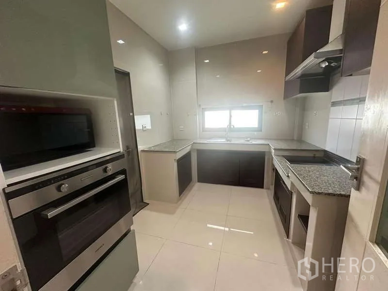 Detached House for rent or sale in Bang Kapi, Bangkok - Separate closed kitchen with built-in ovens, range hood, L-shaped counters and window.