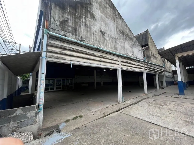 Warehouse for rent in Phra Khanong, Bangkok - Side elevation showing long open loading bay with pillars under a sawtooth roof.