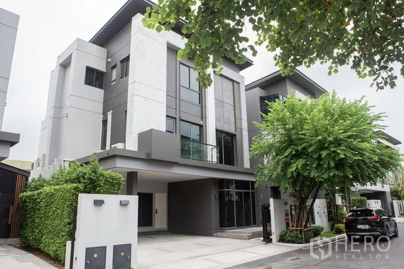 独立式住宅 出租或出售在Bangkok - 正立面视角的三层独栋，带车道与绿篱。