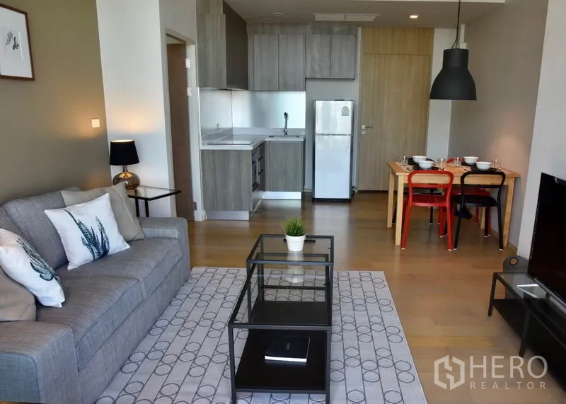 คอนโด ให้เช่าในPhaya Thai, Bangkok - โถงนั่งเล่นแบบโอเพนแพลนพร้อมครัวบิวท์อิน ตู้เย็น และชุดโต๊ะทานอาหาร พื้นไม้โทนอ่อน.