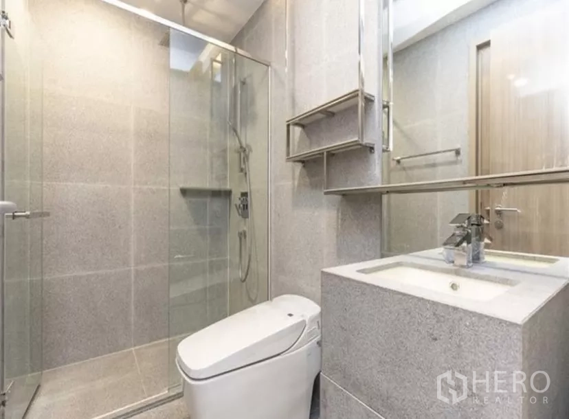 公寓 出租在Ratchathewi, Bangkok - 现代卫浴，玻璃淋浴房、台盆柜与坐便，灰色石材饰面。