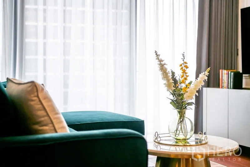 公寓 出租或出售在Watthana, Bangkok - 明亮客厅，水鸭绿色沙发、圆形大理石茶几与落地窗纱帘