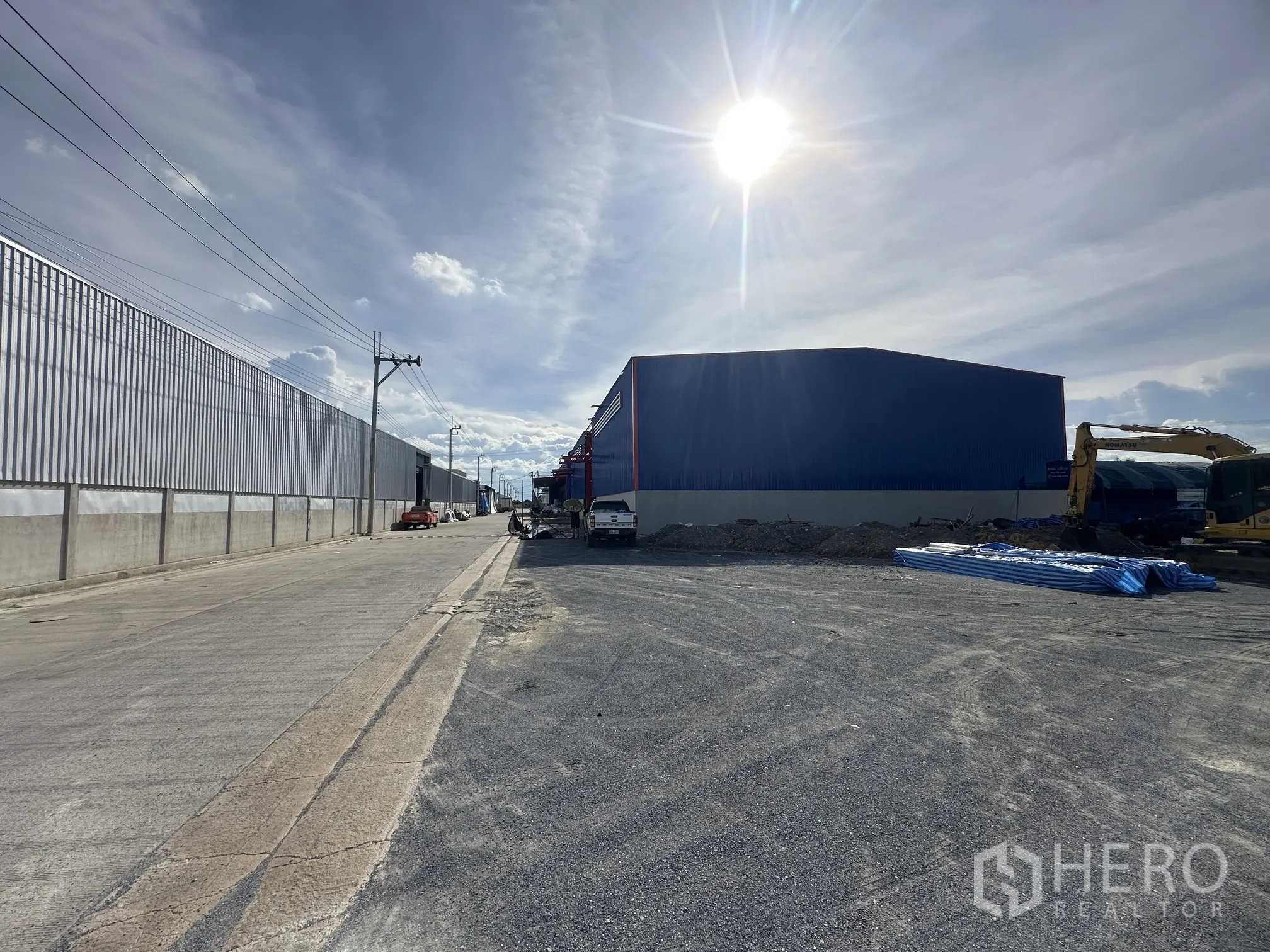 Land for sale in Sai Noi, Nonthaburi - Industrial street frontage showing prepared ground and construction equipment.