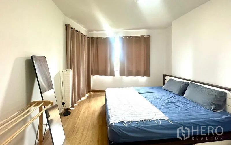 คอนโด ให้เช่าในHuai Khwang, Bangkok - ห้องนอนที่สองพร้อมเตียง โคมไฟพื้น และผ้าม่านทึบแสง