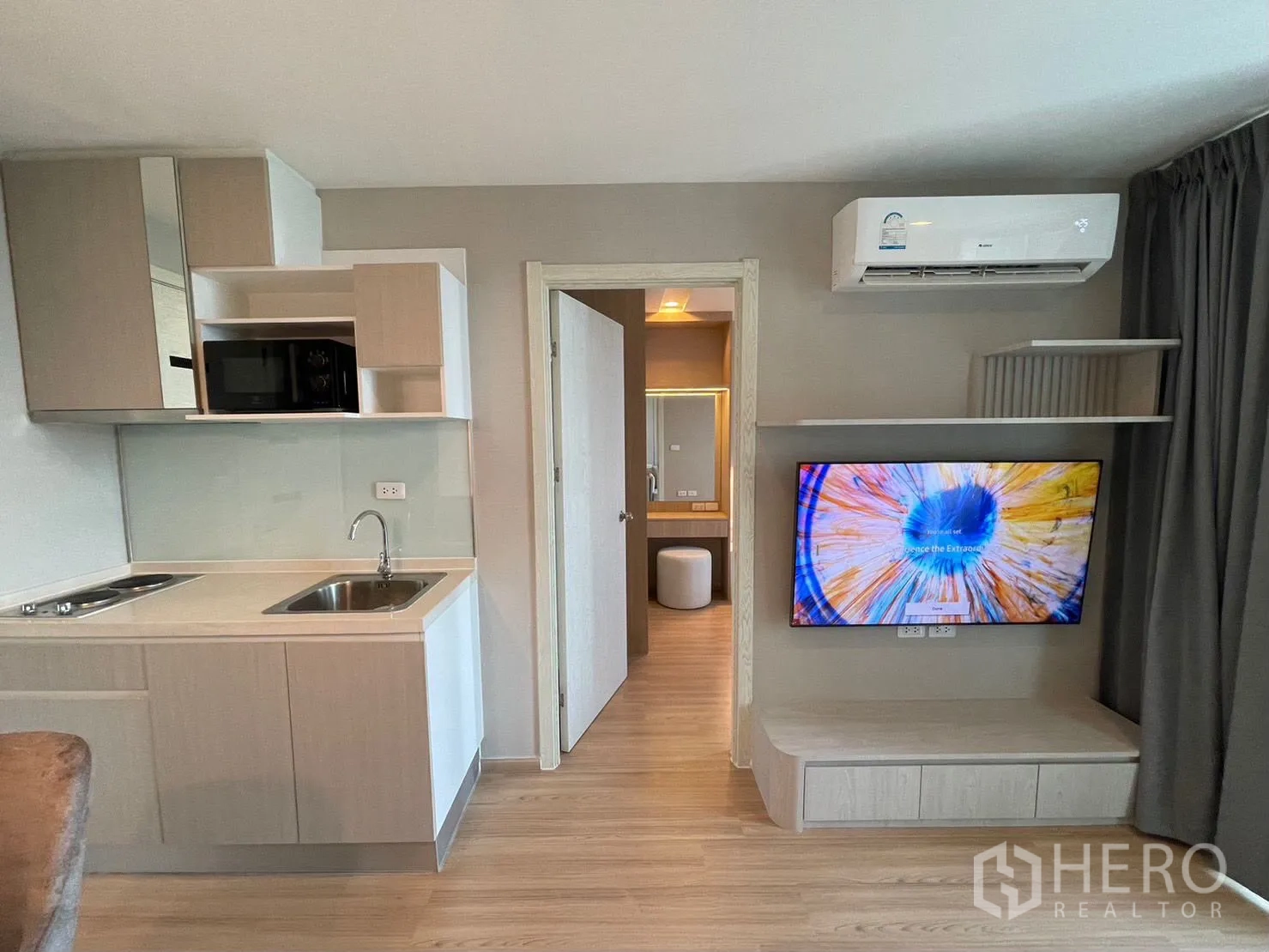 คอนโด for rent in Suan Luang, Bangkok - ครัวขนาดกะทัดรัดพร้อมอ่างล้างจานและตู้เก็บของ ตรงข้ามทีวีติดผนัง และทางเข้าห้องน้ำ