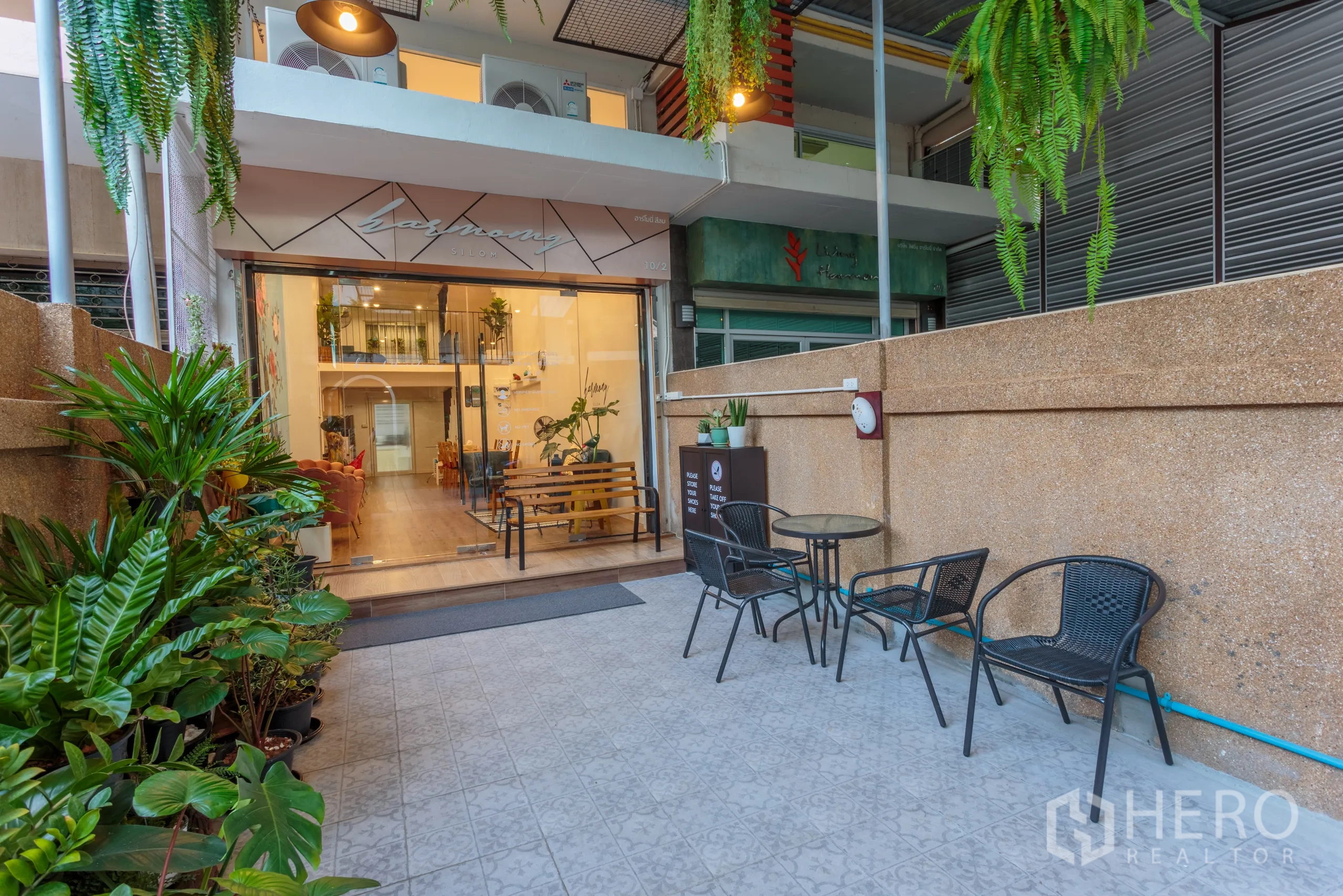 Townhouse for rent in Bang Rak, Bangkok - Glass-front townhouse with patio seating and lush plants at the entrance.