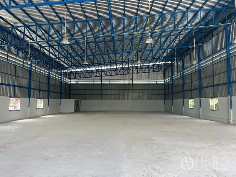 Warehouse for rent in Min Buri, Bangkok - Spacious clear-span warehouse interior with blue steel trusses and high-bay lighting.