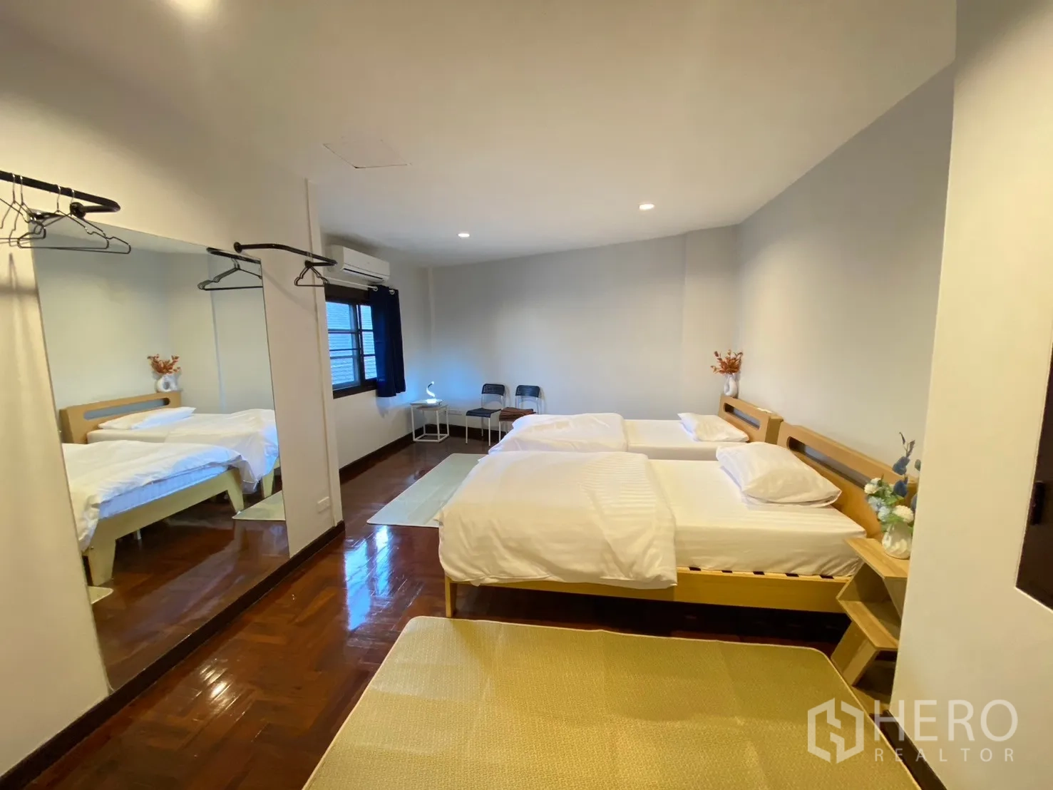 Home Office for rent in Watthana, Bangkok - Twin-bed bedroom with large mirrors, wood floors and a wall-mounted clothes rail.