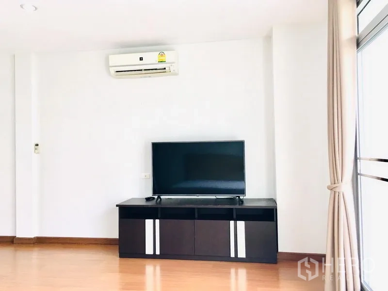 联排别墅 出租在Prawet, Bangkok - 房间设电视柜与壁挂空调，旁有落地窗。