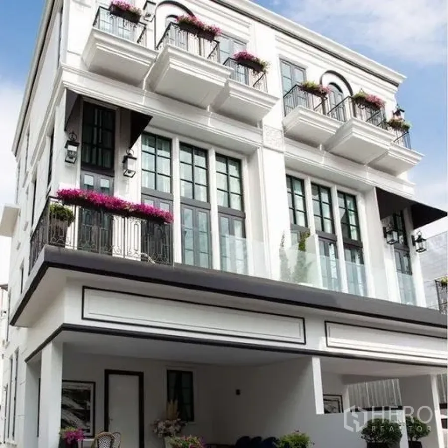 Townhouse for sale - Modern multi-level townhouse facade with large windows, flowered balconies and a covered carport.