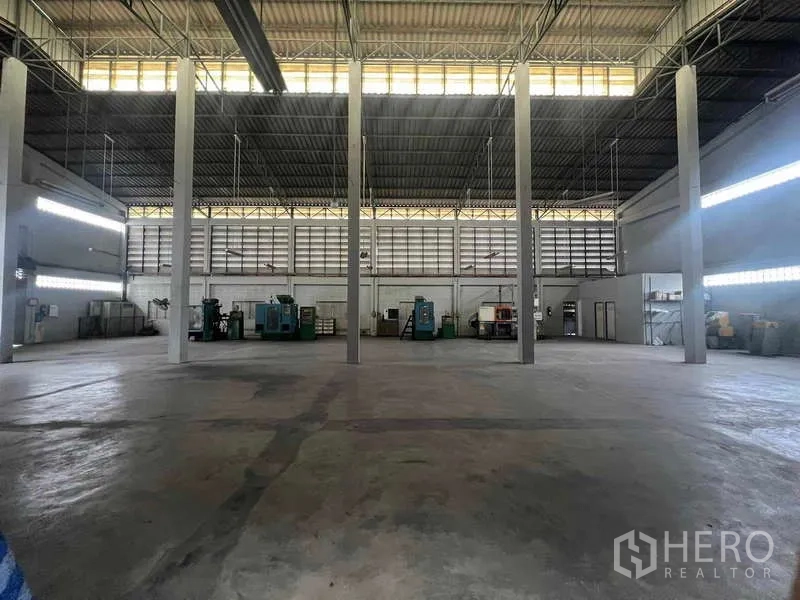 Warehouse for rent in Lam Luk Ka, Pathum Thani - Front exterior of a white warehouse with multiple roller shutters and a broad forecourt.
