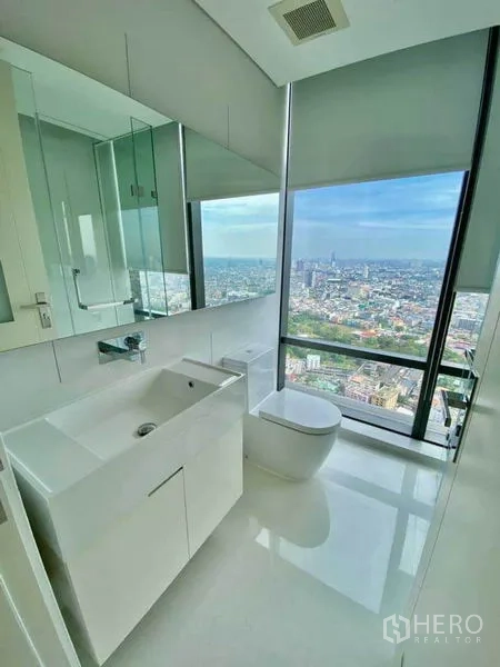 Condominium for rent in Sathon, Bangkok - Bright secondary bathroom with large vanity, toilet and a wide city view window.