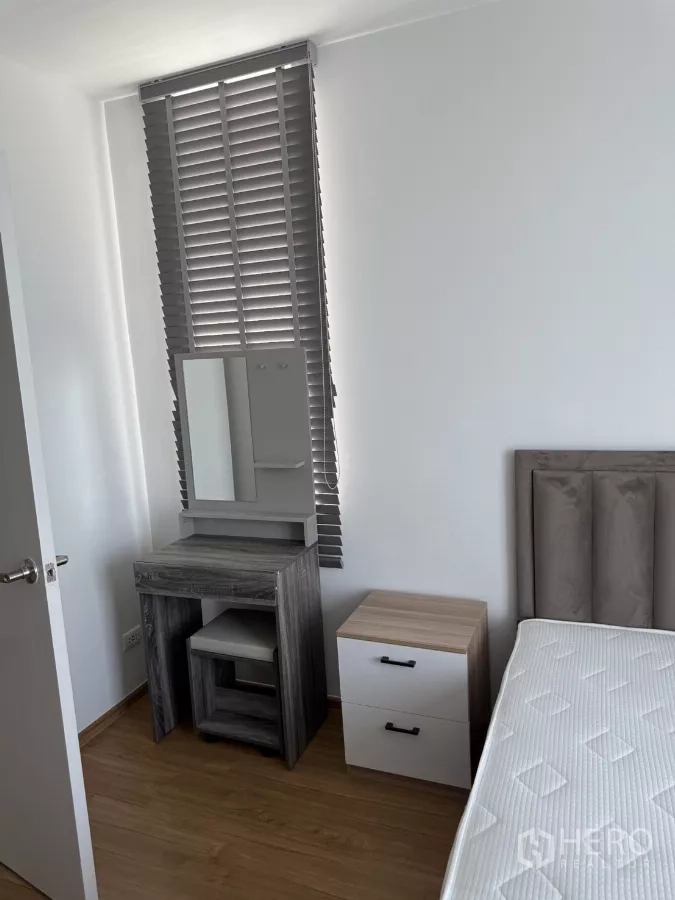 Townhouse for rent or sale in Bang Phli, Samut Prakan - Bedroom corner with dressing table, bedside cabinet and tall louvered window.