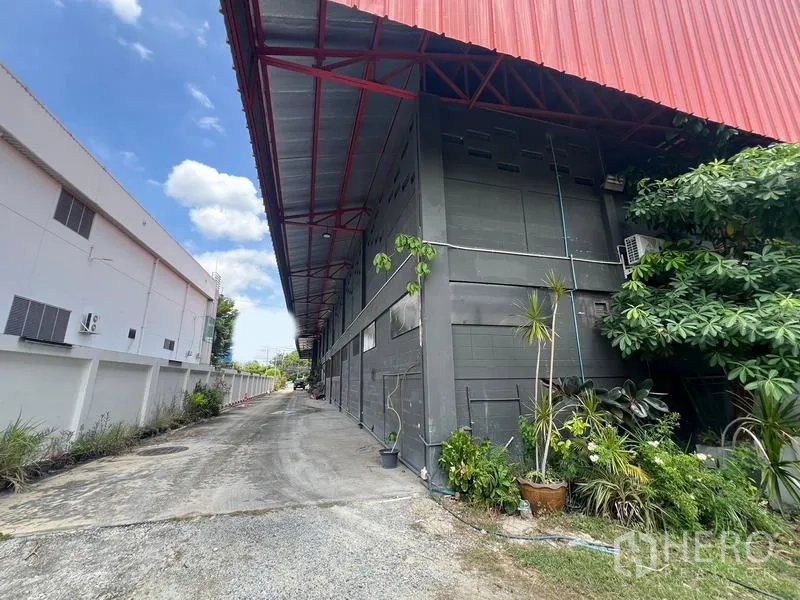 โชว์รูม ให้เช่าในMueang Samut Prakan, Samut Prakan - ทางเดินด้านข้างอาคาร หลังคายื่นสีแดงและต้นไม้รอบอาคาร