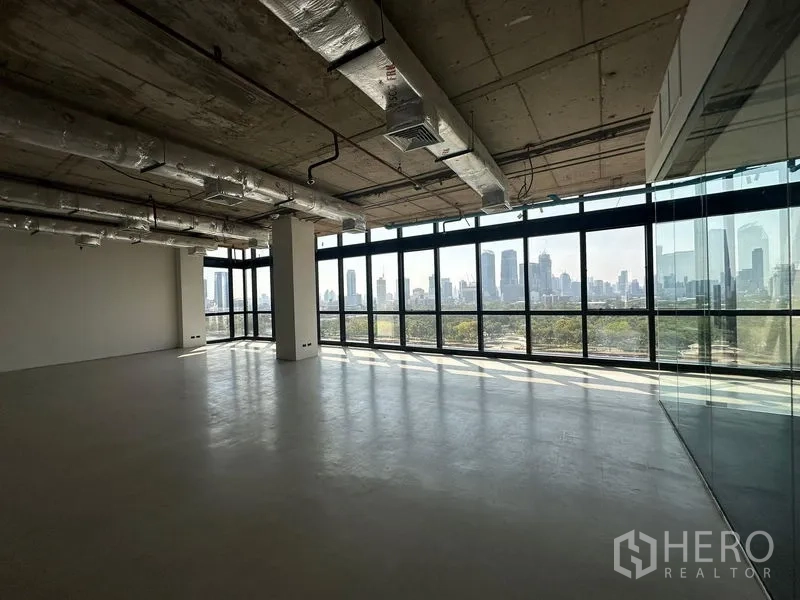 Office Space for rent in Watthana, Bangkok - Open workspace with full-height glazing, industrial ceiling, glass partition and wide city and park vistas.