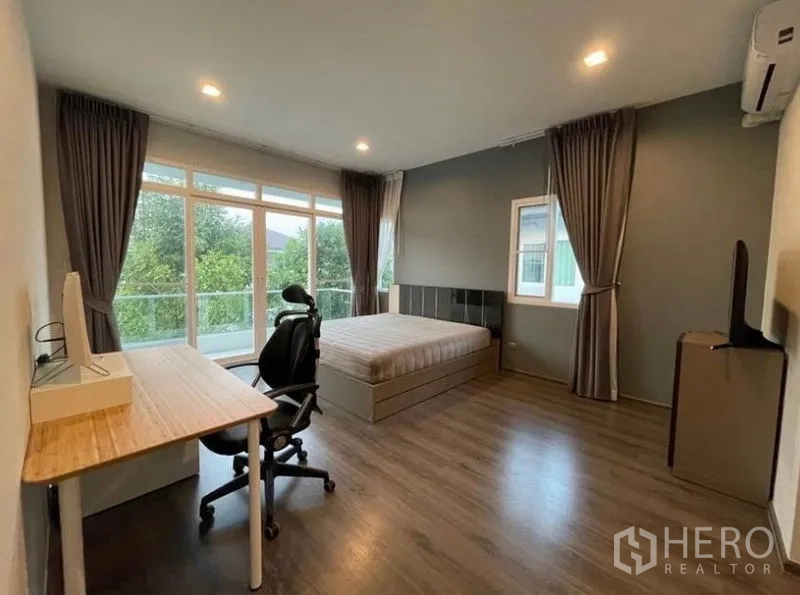 บ้าน ให้เช่าในLat Krabang, Bangkok - ห้องนอนมาสเตอร์กว้าง มีโต๊ะทำงาน เก้าอี้ หน้าต่างบานใหญ่ และประตูออกระเบียง