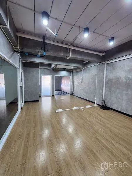 Office Space for rent or sale in Bueng Kum, Bangkok - Industrial-style office room with wood floors, concrete walls, ceiling lights and sliding glass partitions.