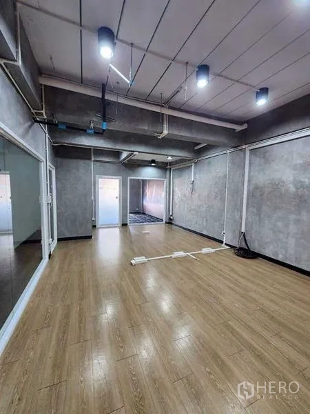 Office Space for rent or sale in Bueng Kum, Bangkok - Industrial-style office room with wood floors, concrete walls, ceiling lights and sliding glass partitions.
