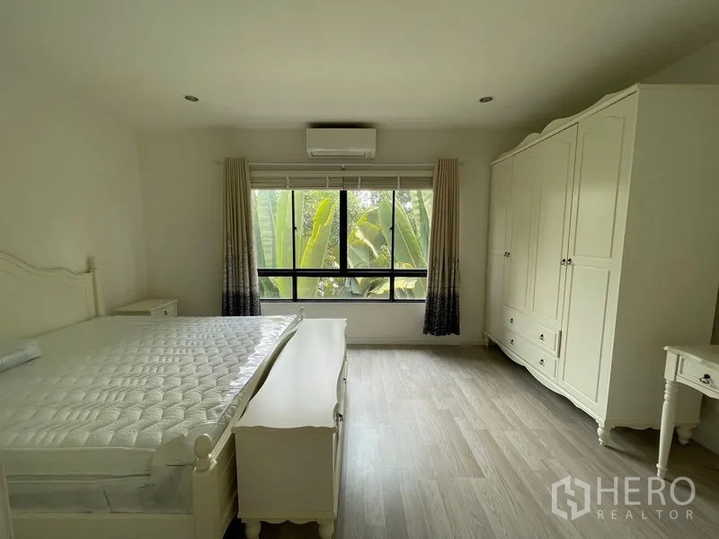 Townhouse for rent in Bang Kapi, Bangkok - Spacious master bedroom with large wardrobe, bed and greenery view through wide window.