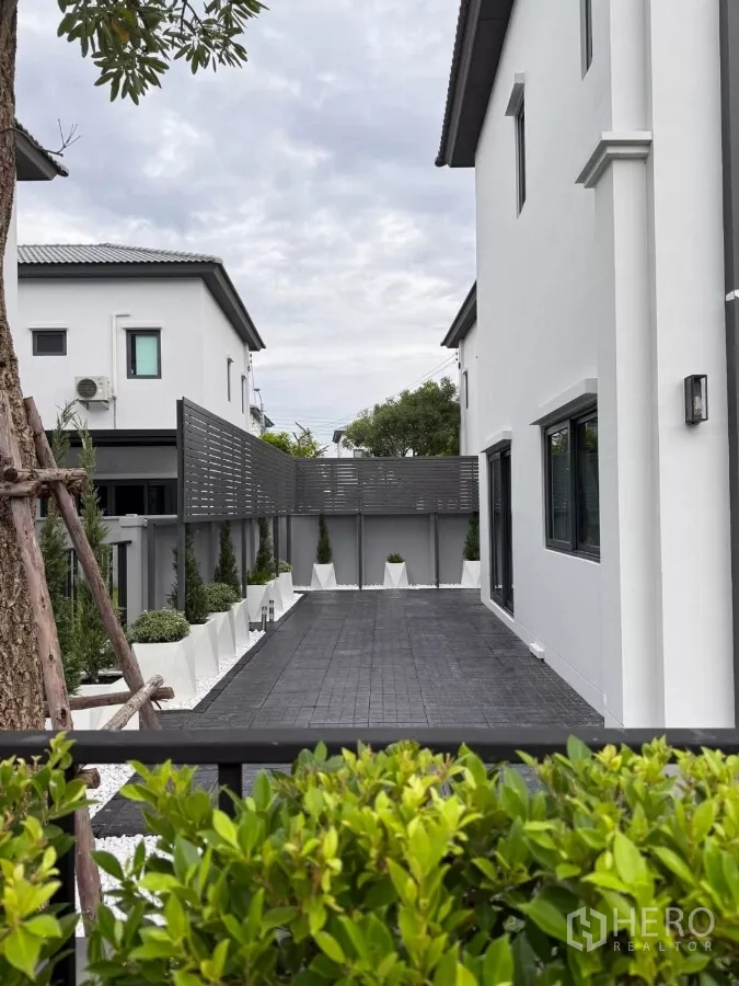 Detached House for rent in Bang Phli, Samut Prakan - Paved side yard with privacy screen, white pebble planters and low‑maintenance landscaping.