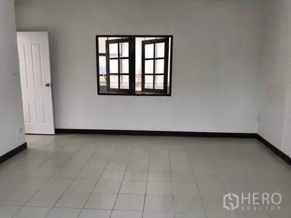 货栈 出租在Pathum Thani - 空置的瓷砖办公室，白色墙面与中央窗户。