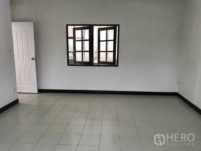 货栈 出租在Pathum Thani - 空置的瓷砖办公室，白色墙面与中央窗户。