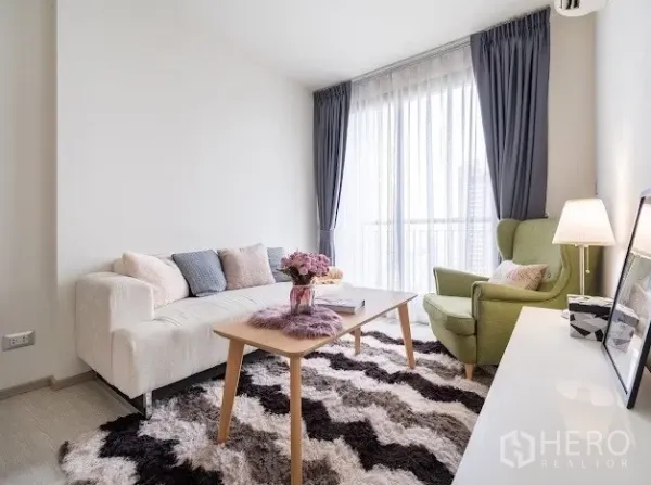 公寓 出售在Khlong Toei, Bangkok - 客厅设落地窗与纱帘，米色沙发、绿色单椅，可见阳台景致。