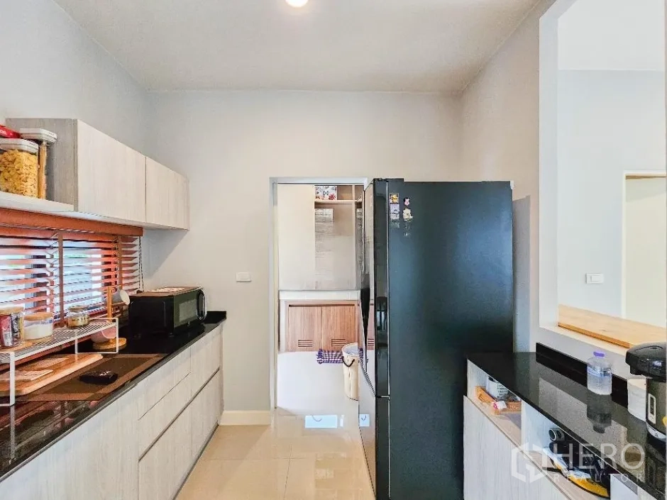 บ้าน ขายในLam Luk Ka, Pathum Thani - ห้องครัวหลัก เคาน์เตอร์หินสีดำ ตู้เก็บของครบ และตู้เย็นขนาดใหญ่