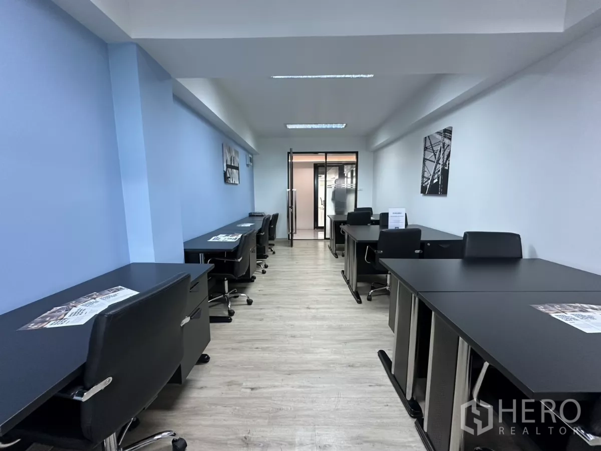 Office Space for rent in Watthana, Bangkok - Open-plan office showing multiple desks with brochures and a glass entry to the meeting area.