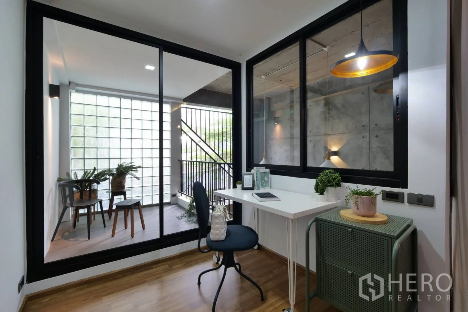 Townhouse for rent in Khlong Toei, Bangkok - Compact home office beside a glass wall opening to a balcony with glass blocks.