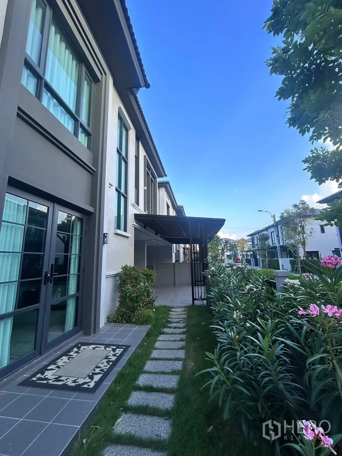 Semi-detached House for rent in Bang Phli, Samut Prakan - Contemporary exterior with tall windows, side garden path, and covered carport.