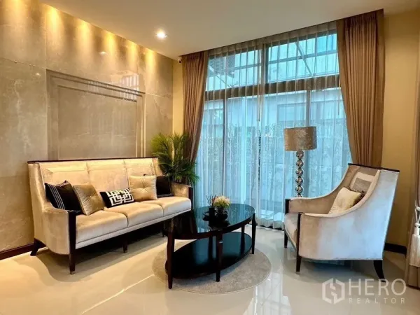 独立式住宅 出租 - 温馨客厅一角，奶油色沙发与扶手椅，落地窗与柔和灯光。