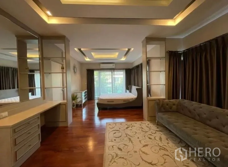 Detached House for rent or sale in Bang Phli, Samut Prakan - Spacious master suite with sitting area, balcony doors, wood flooring and ambient ceiling lights.