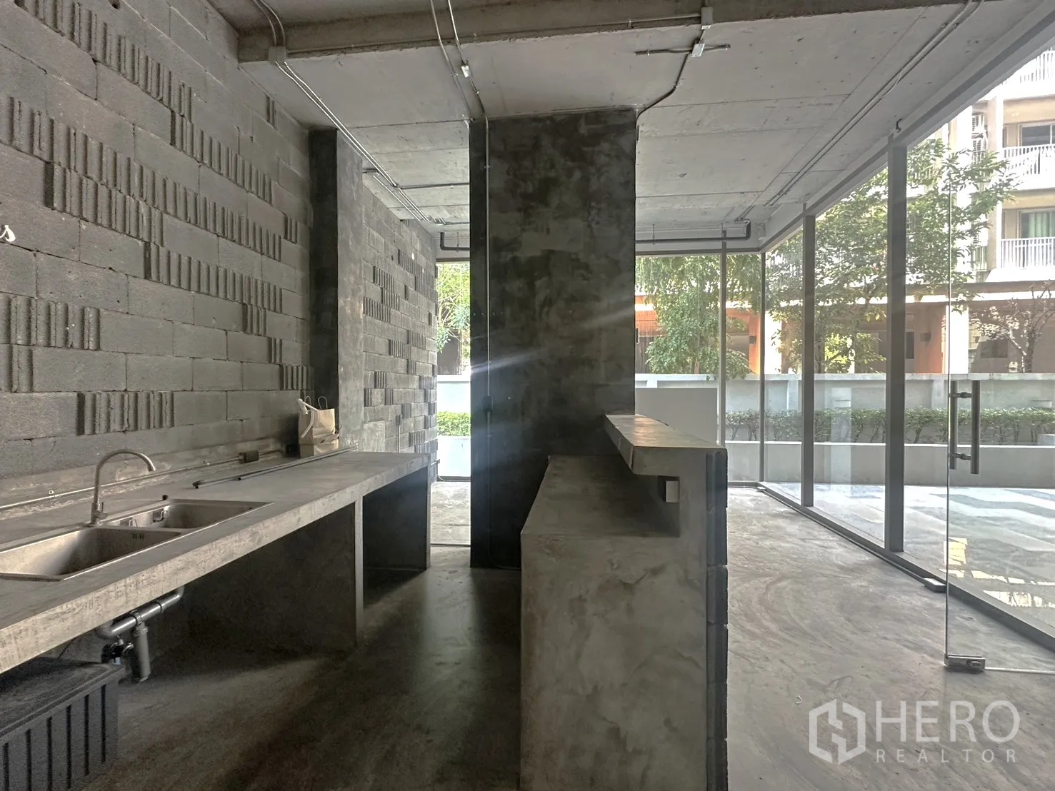 พื้นที่ขายปลีก ให้เช่าในPhra Khanong, Bangkok - เคาน์เตอร์คอนกรีตพร้อมอ่างล้างสแตนเลส หันสู่หน้าร้านกระจกมองเห็นต้นไม้