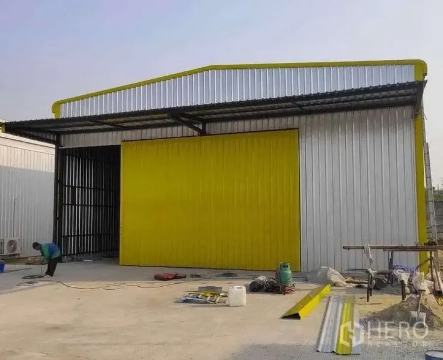 货栈 出租在Khlong Sam Wa, Bangkok - 金属板外墙仓库，醒目黄色推拉门与雨棚，前方混凝土装卸区，曼谷Khlong Sam Wa。