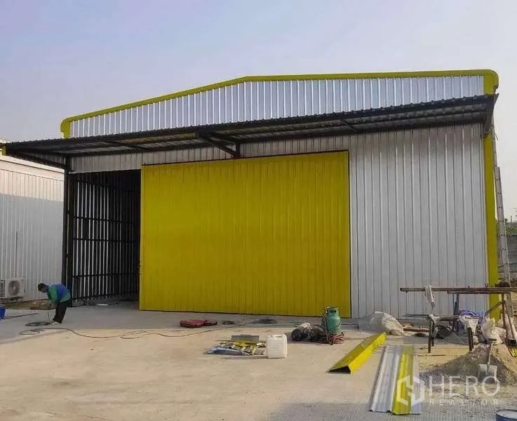 货栈 出租在Khlong Sam Wa, Bangkok - 金属板外墙仓库，醒目黄色推拉门与雨棚，前方混凝土装卸区，曼谷Khlong Sam Wa。