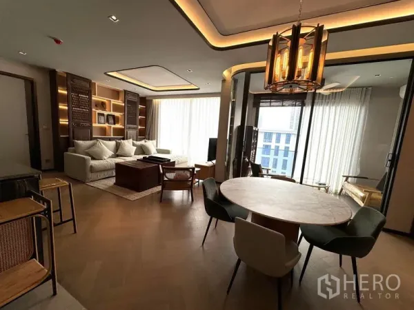 Condominium for rent in Watthana, Bangkok - Open-plan living and dining area with cove lighting, round table, and floor-to-ceiling windows.