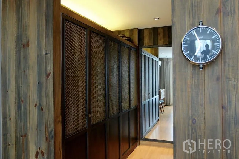 Condominium for sale in Watthana, Bangkok - Walkway lined with full-height mesh-door wardrobes and a large mirror.